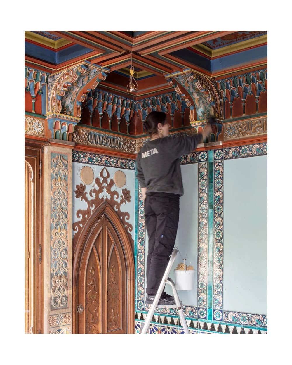 A conservator-restorer working on the polychrome architectural decoration of a nineteenth-century salon.